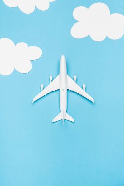 Beyaz bulutlu mavi zemin üzerinde beyaz uçak modelinin üst görünümü