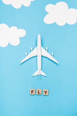 Mavi gökyüzü arka planında kelime sineği olan uçak modelinin ve küplerin üst görünümü