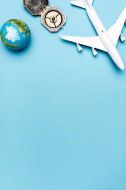 top view of white plane model, compass, globe on blue background clipart