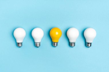 top view of white and yellow light bulbs on blue background clipart