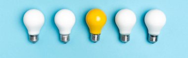 top view of white and yellow light bulbs on blue background, banner clipart