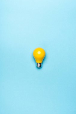top view yellow light bulb on blue background clipart