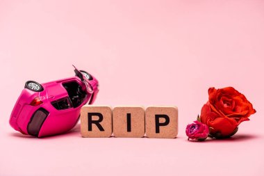crashed car and word rip with flowers on pink background clipart