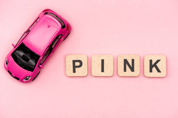 вид на игрушечный автомобиль и слово розовый на кубиках