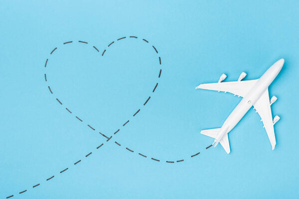 top view of white plane model and heart on blue background