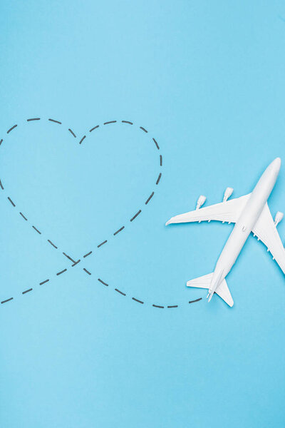 top view of white plane model and heart on blue background
