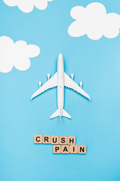 top view of plane model and cubes with word crush pain on blue sky background