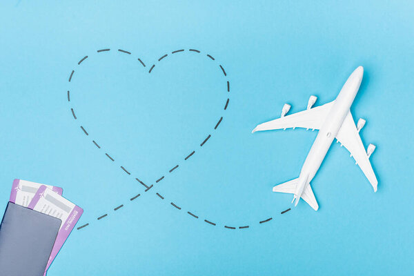 top view of white plane model and tickets on blue background