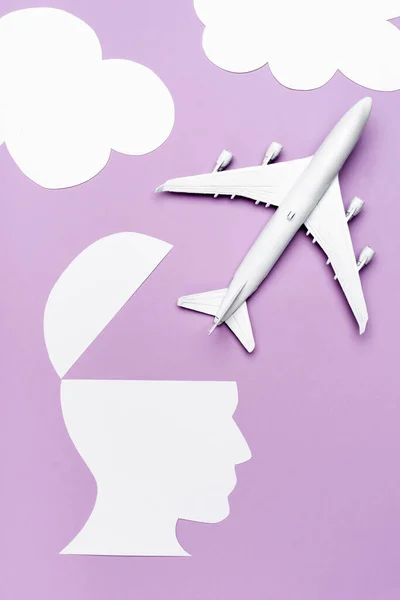 白い飛行機の模型と紙の上から見た紫色の背景に人間の頭を切り取り — ストック写真