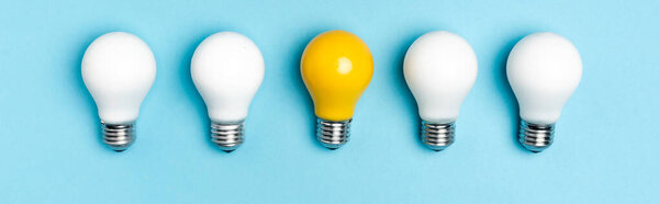 top view of white and yellow light bulbs on blue background, banner