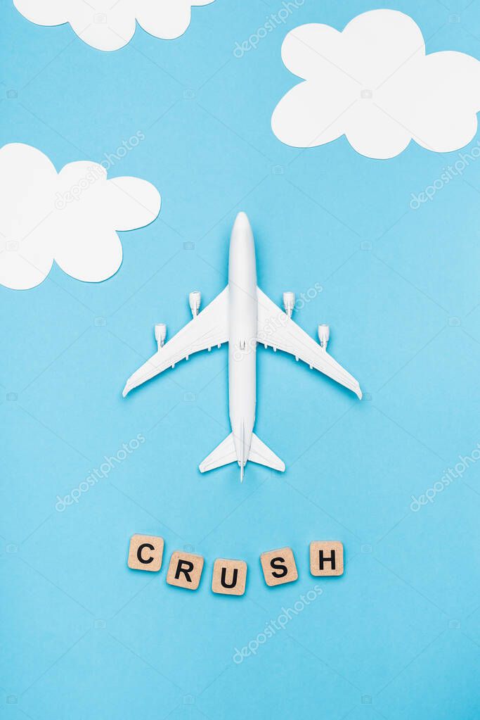 top view of plane model and cubes with word crush on blue sky background