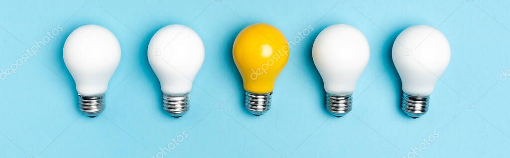 top view of white and yellow light bulbs on blue background, banner