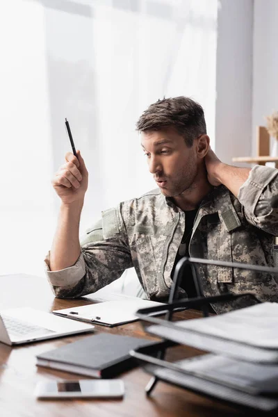 Έκπληκτος Στρατιώτης Στολή Κρατώντας Στυλό Κοντά Στο Laptop Smartphone Θολή — Φωτογραφία Αρχείου