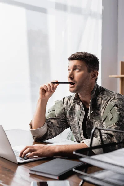 Pensive Soldier Uniform Holding Pen Laptop Smartphone Blurred Foreground — Stock Photo, Image