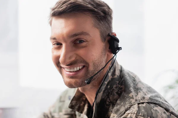 happy military man in uniform and headset smiling in office