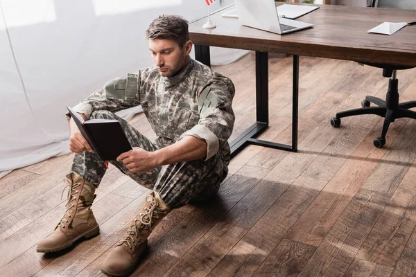 专心致志的军人 身穿制服 拿着练习本 坐在桌旁的地板上 — 图库照片