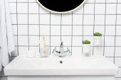 Zubní pasta se zubním kartáčkem, rostlinami a kosmetickým krémem na umyvadle v moderní koupelně 