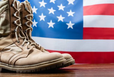 army boots near american flag on blurred background clipart