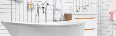 Modern banyoda beyaz küvet, havlular, tuvalet malzemeleri, afişler. 