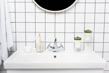 Modern banyodaki lavaboda diş fırçası, bitki ve kozmetik kremi ile diş macunu. 
