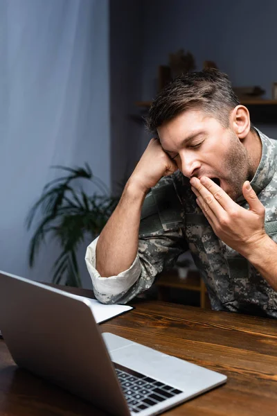 Exhausto Militar Uniforme Cubriendo Boca Mientras Bosteza Cerca Computadora Portátil — Foto de Stock