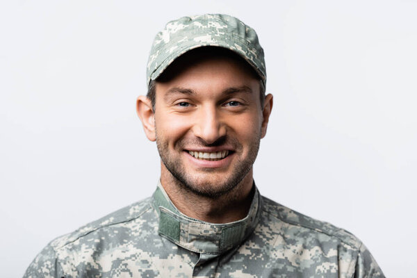 happy military man in uniform and cap smiling isolated on white