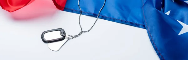 blank metallic badge on chain near american flag on white, banner