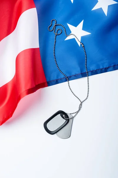 blank metallic badge on chain near american flag on white 