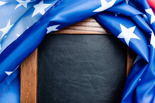 close up of blank chalkboard near flag of american with stars and stipes 