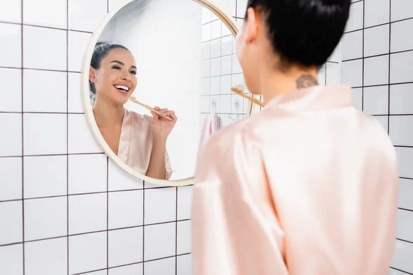 Donna Sorridente Accappatoio Raso Guardando Specchio Mentre Tiene Spazzolino Denti — Foto Stock