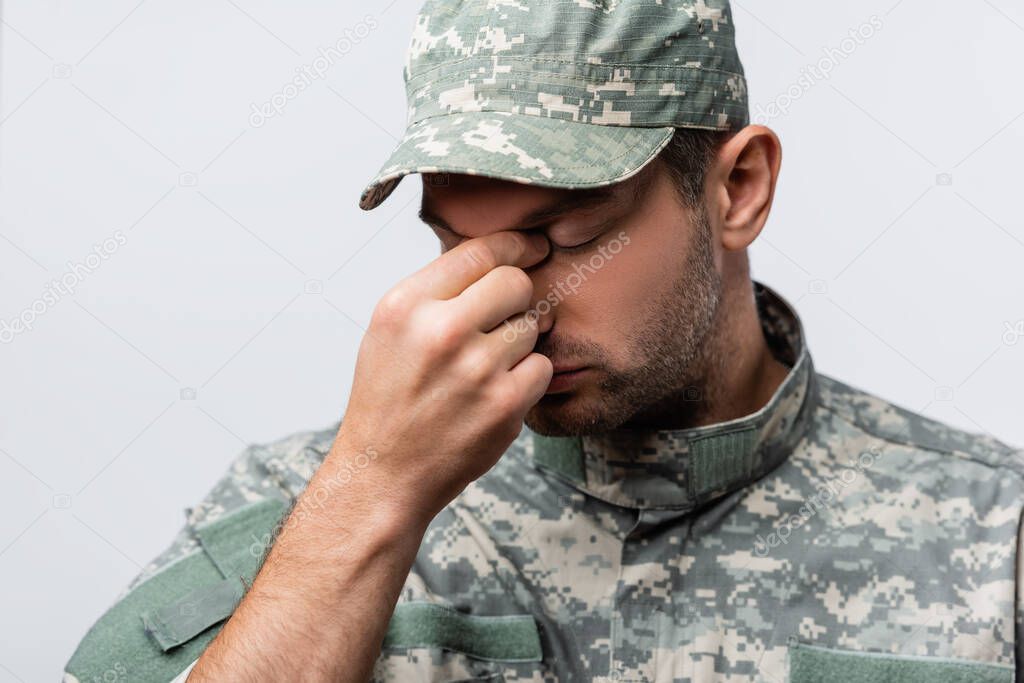 sad military man in uniform and cap wiping tears isolated on white