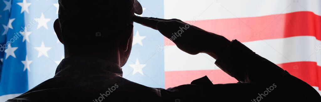 back view of patriotic military man in uniform giving salute near american flag on background, banner