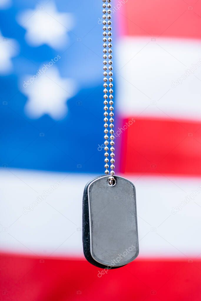 close up of blank silver badge on chain near american flag on blurred background
