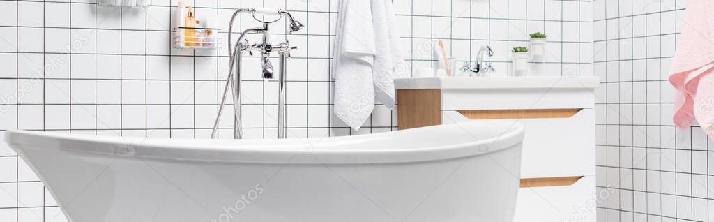 White bathtub in modern bathroom with towels and toiletries, banner 