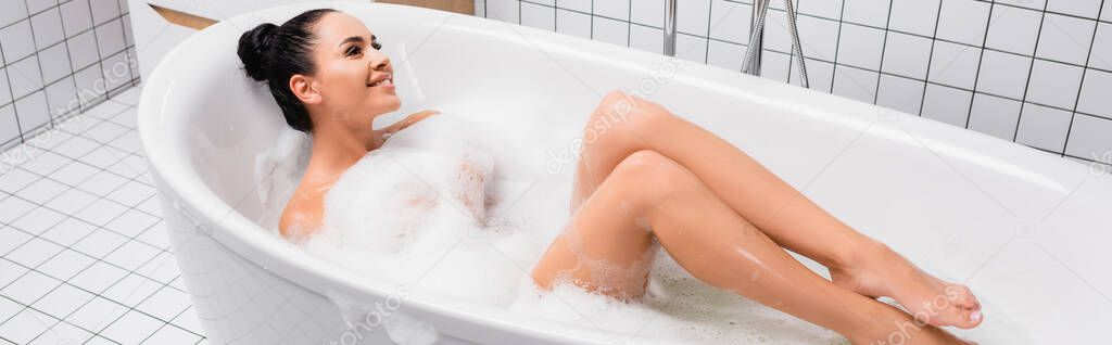 Cheerful woman lying in bathtub with soapsuds, banner 