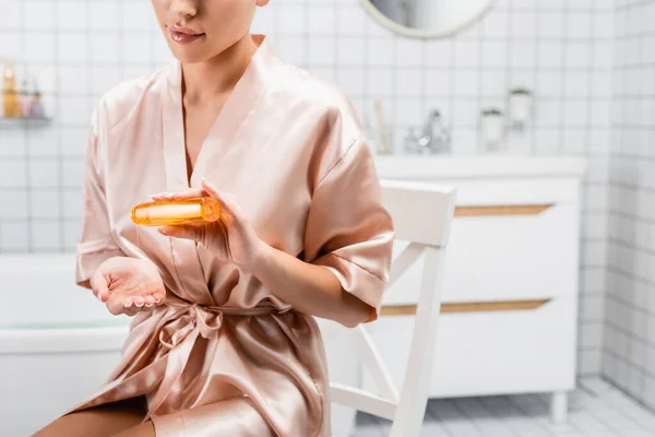 Cropped View Woman Silk Bathrobe Pouring Cosmetic Oil Bathroom — Stock Photo, Image