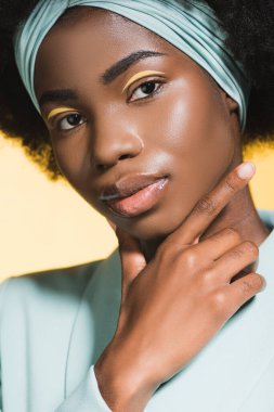 Afro-Amerikalı, mavi kıyafetli genç bir kadın sarıda izole edilmiş. 