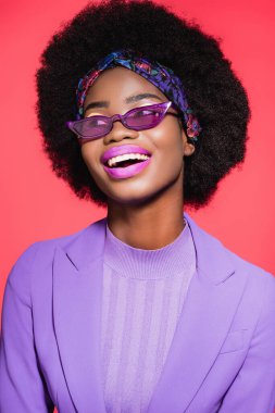 Mutlu Afro-Amerikan genç bayan Mor şık kıyafet ve güneş gözlüğü kırmızı izole