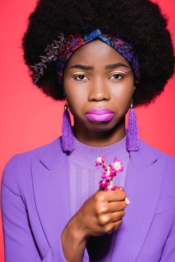 Üzgün, Afro-Amerikalı, mor giyinmiş, çiçekli, kırmızı renkli genç bir kadın.
