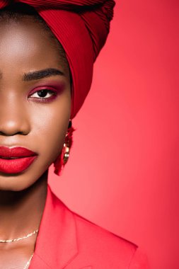 Kırmızıda izole edilmiş türban ve şık giyimli Afrikalı Amerikalı genç kadın manzarası.
