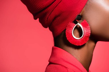 Kırmızıda izole edilmiş şık küpeli Afro-Amerikan genç kadın manzarası.