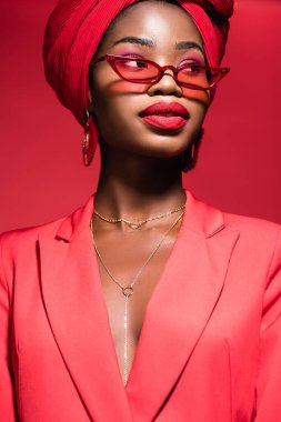 Kırmızı giysili, güneş gözlüklü ve türbanlı Afro-Amerikan genç kadın.