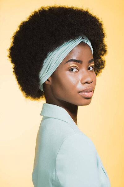 profile of african american young woman in blue stylish outfit isolated on yellow 