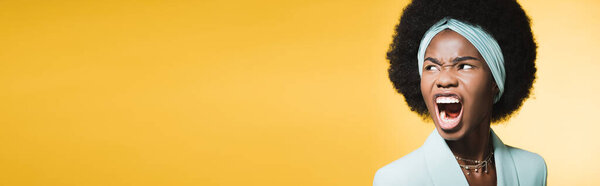 angry african american young woman in blue stylish outfit yelling isolated on yellow, banner