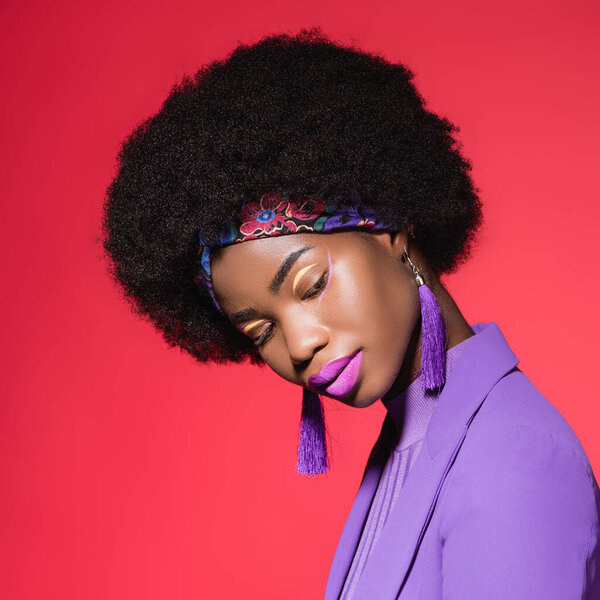 african american young woman in purple stylish outfit isolated on red