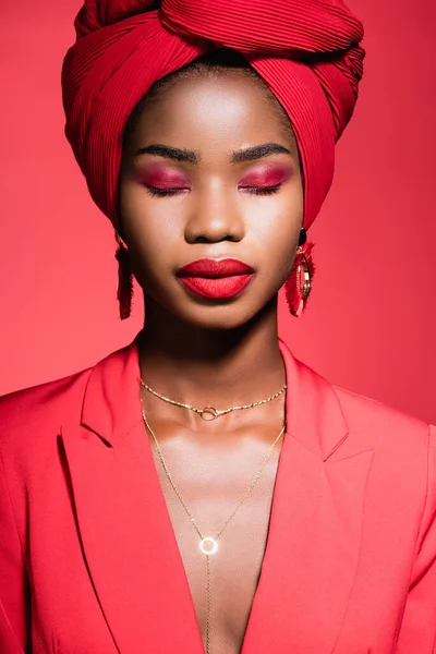 stock image african american young woman in stylish outfit and turban with closed eyes isolated on red