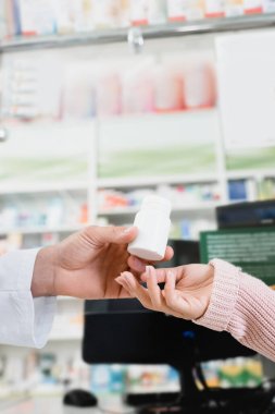 cropped view of pharmacist giving bottle with pills to customer clipart