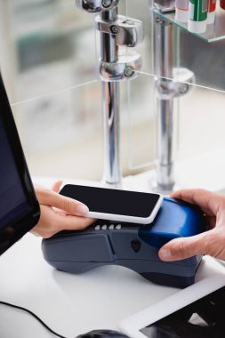 Marketteki ödeme terminalinde elinde akıllı telefon olan bir kadın görüntüsü. 
