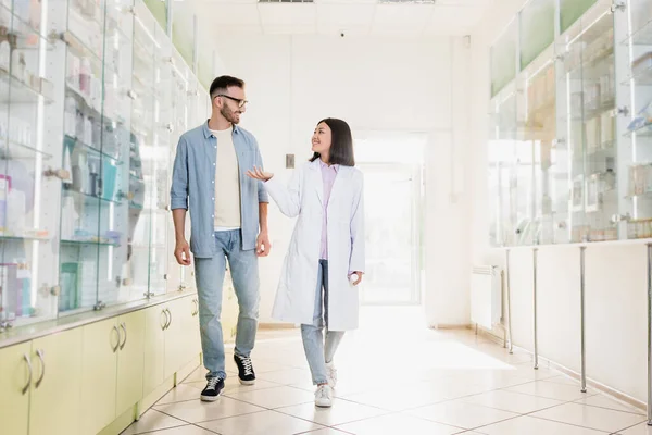 Full Length Cheerful Asian Pharmacist White Coat Walking Customer Drugstore — Stock Photo, Image