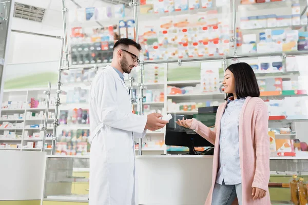 Barbudo Farmacéutico Gafas Blanco Abrigo Dando Botella Con Pastillas Asiático — Foto de Stock